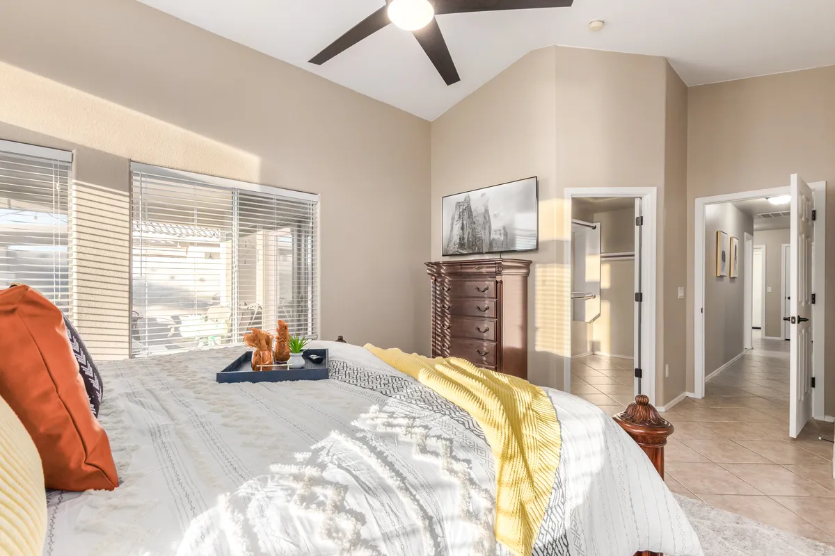 A serene bedroom featuring a bed, a dressing table, large windows allowing gentle sunlight, and tasteful paintings. The calm, cozy mood makes this room an ideal space for personal retreat and relaxation.