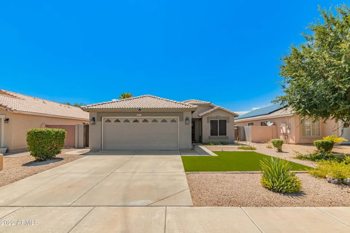 A bright and inviting exterior view of the home's front entrance, featuring a garage door and a landscaped yard. The welcoming facade sets a friendly tone and suggests easy access to surrounding amenities.