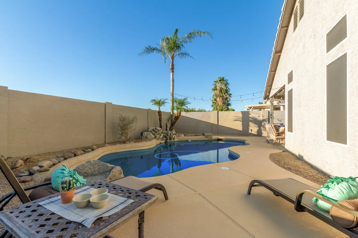 A sparkling swimming pool surrounded by palm trees and several lounge chairs, all basking in the warmth of the Arizona sun. The scene hints at relaxation and leisurely afternoons spent outdoors.