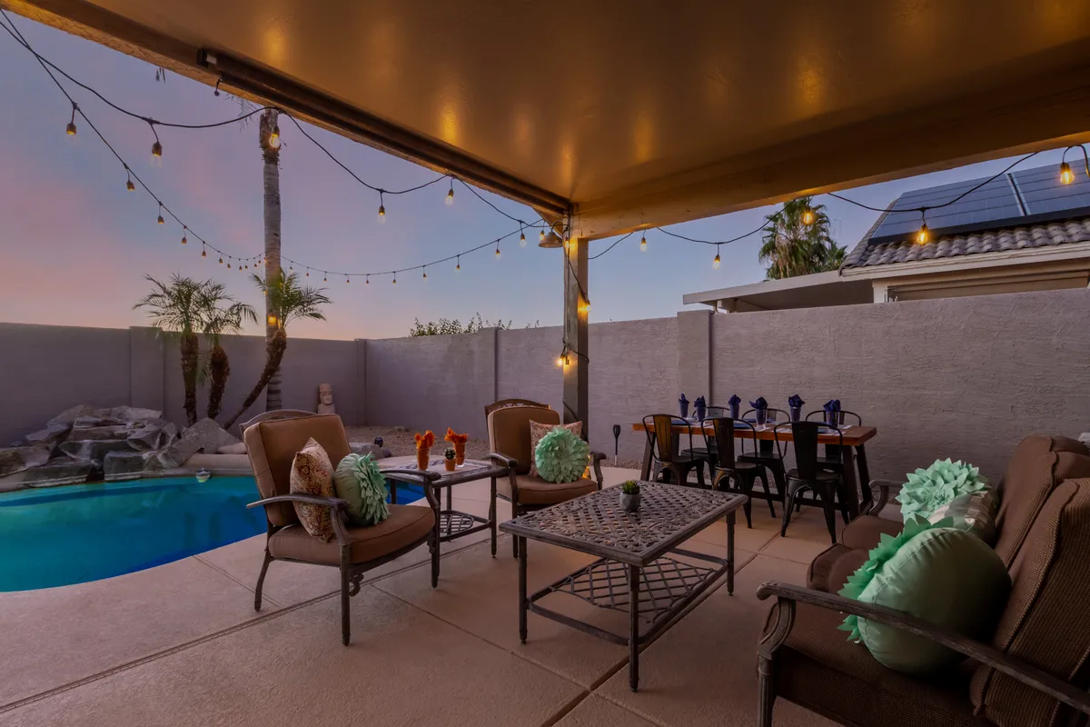 This image spotlights an inviting backyard pool surrounded by comfortable outdoor seating and string lights overhead, creating a warm setting ideal for family fun. The pool area is ready for both daytime swims and relaxing evening gatherings, with a layout that encourages togetherness.