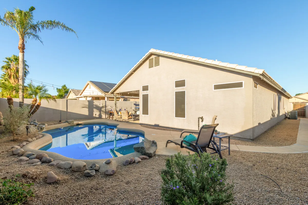 A well-landscaped patio area with a swimming pool, outdoor dining furniture, and lush greenery. The inviting setup encourages morning coffee, afternoon swims, and group meals in a comfortable, social setting.